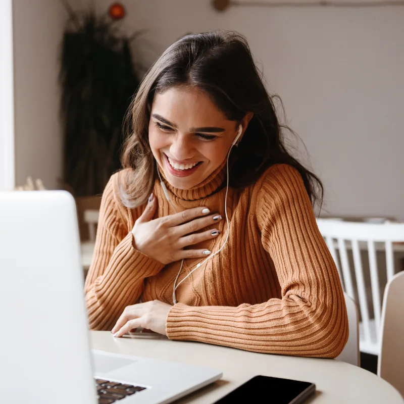 A woman smiling during a video call at her laptop